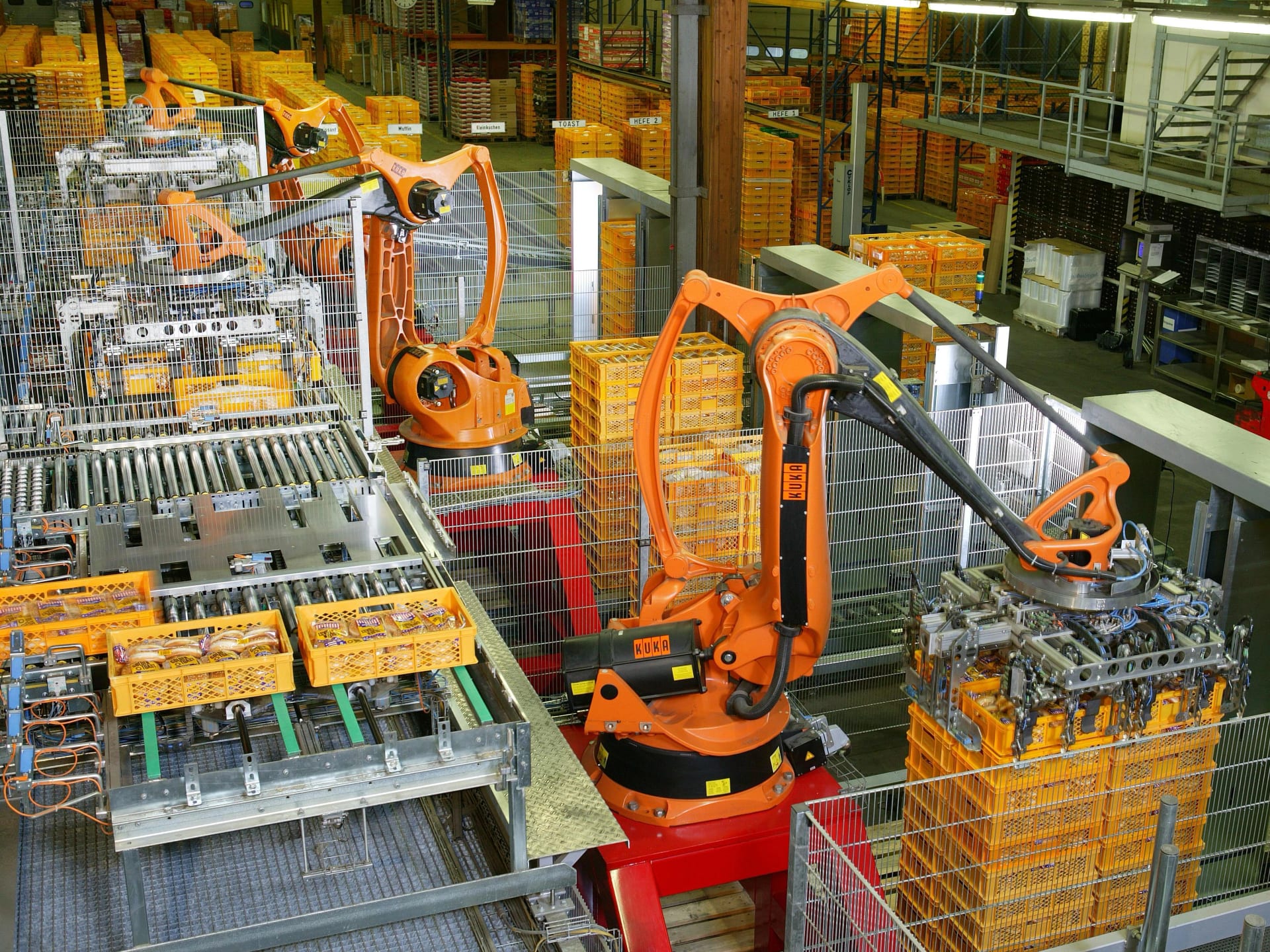 Braços robóticos industriais alaranjados operando sobre uma esteira de paletização numa fábrica